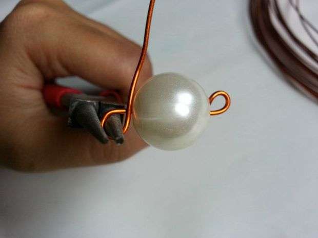 Take the wire from the other end, start twisting it, and then wind it around the bead. Make tight loops at the base of the bead.