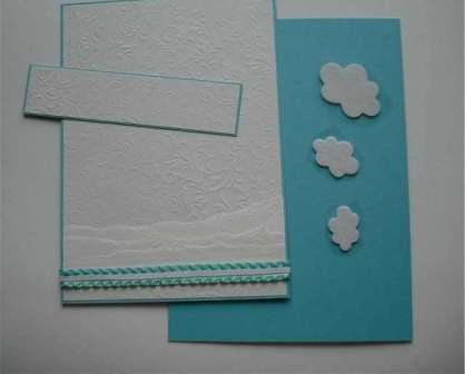 Wytnij prostokąt o wymiarach 13,5 x 2,5 cm z turkusowego papieru i prostokąt o wymiarach 13 x 2,5 cm z białego papieru, który musisz umieścić na górze pocztówki. Wytnij chmury z białego filcu i przyklej je do tego prostokąta.