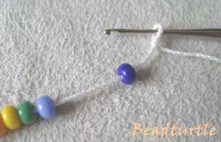 Next, you need to grab the thread directly behind the first bead and pull it into the first loop you just made